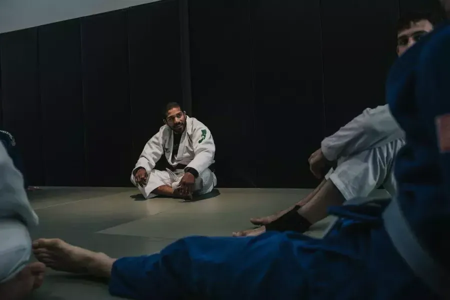 罗慕洛梅洛 sitting on the mat with other fighters.