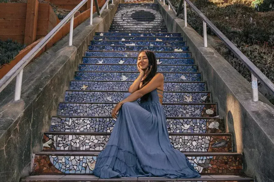 Une femme pose assise sur les escaliers carrelés de la 16e Avenue dans le quartier Sunset de San Francisco.