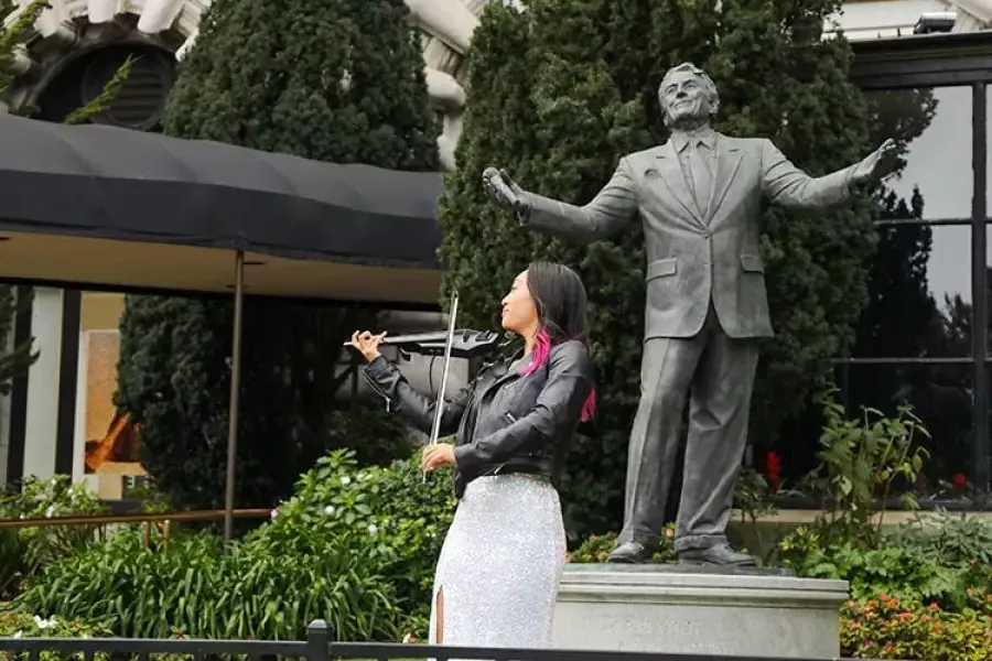 一个女人在费尔蒙特旅馆的托尼·班尼特雕像前演奏小提琴.