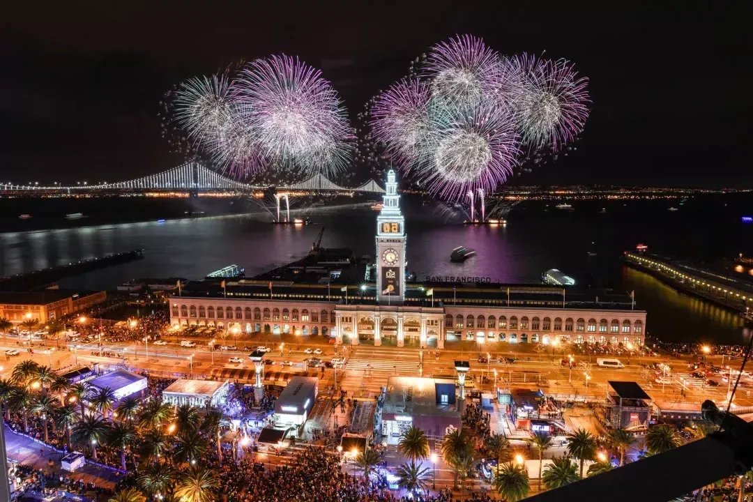Fireworks explode over top of the Ferry Building, with the Bay Bridge in the background. 加州贝博体彩app.